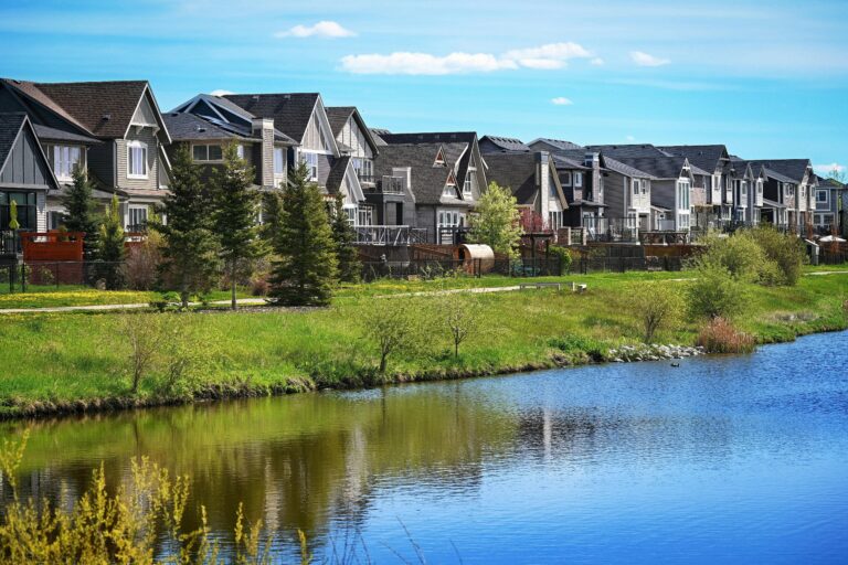Home Modern suburban houses lining a serene pond in Airdrie, Alberta, Canada.
