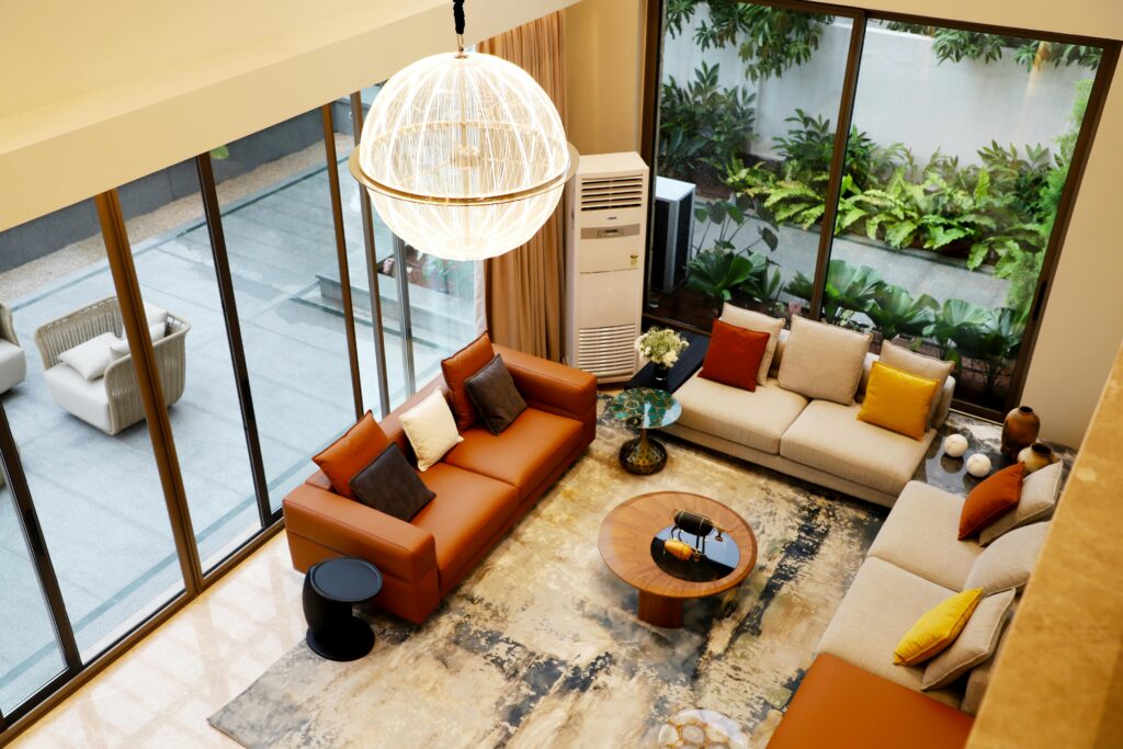 Aerial view of a stylish modern living room with leather sofas, rugs and large windows.