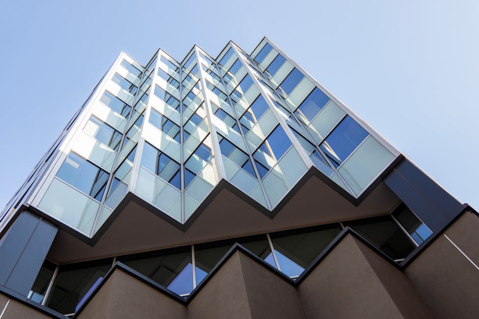 Upward view of a modern geometric building facade against a clear sky.