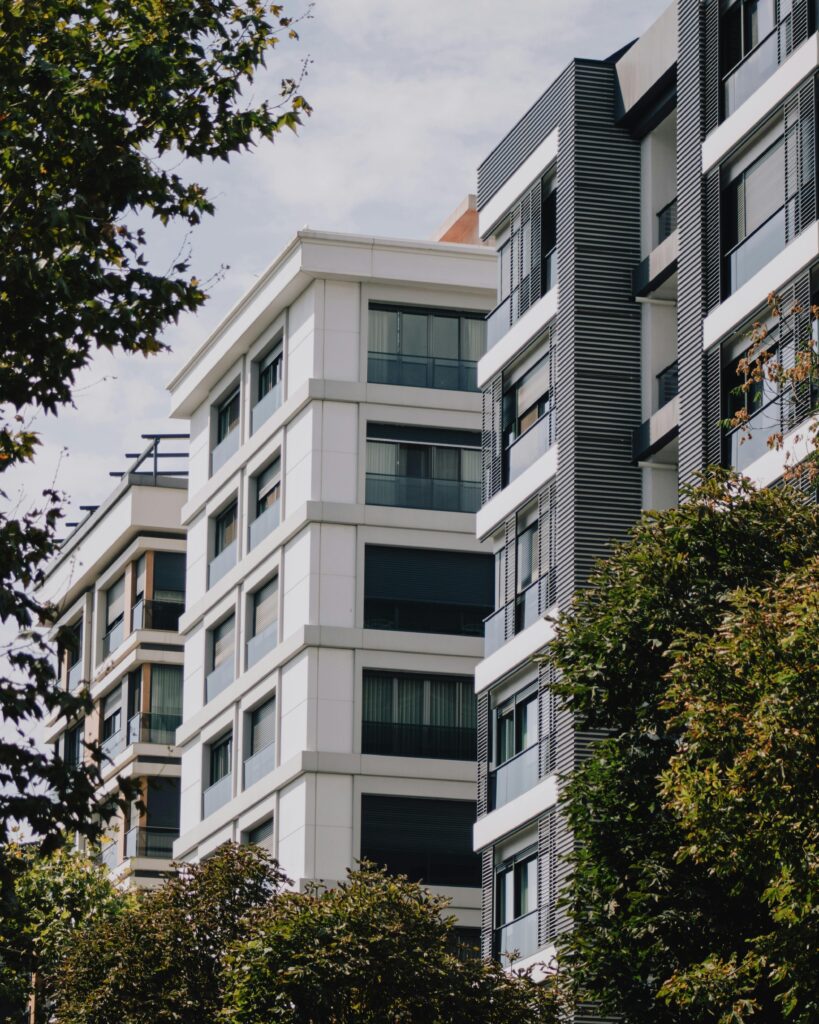 Contemporary apartment structures surrounded by lush trees during the day.