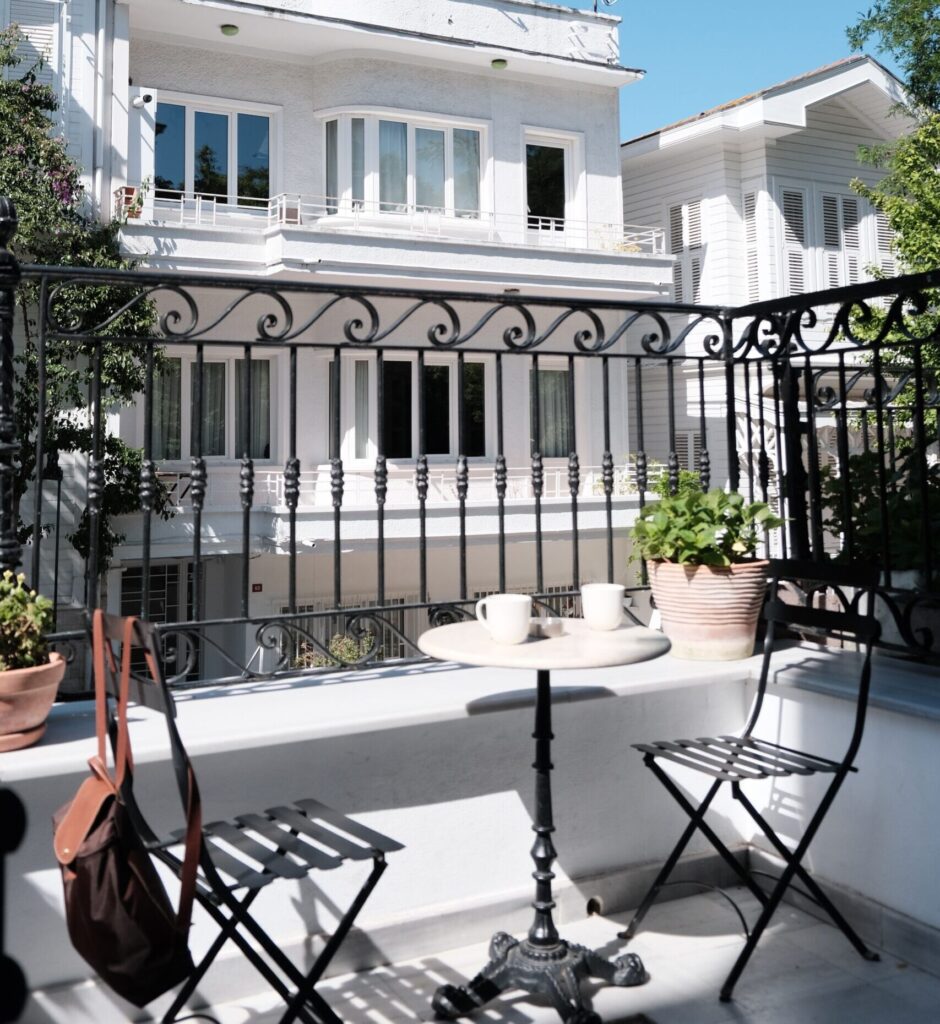 Bright terrace with classic white architecture and cozy seating, perfect urban retreat.